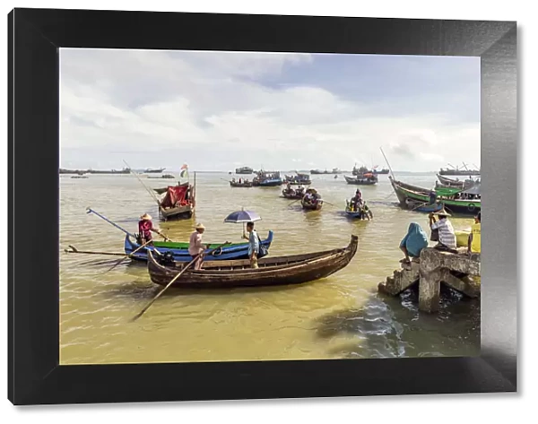 Sampans and other small boats in Sittwe harbour, with people standing on the shore