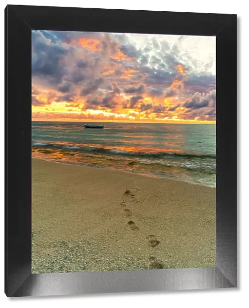 African sunset over footprints on tropical sand beach, Le Morne Brabant, Black River
