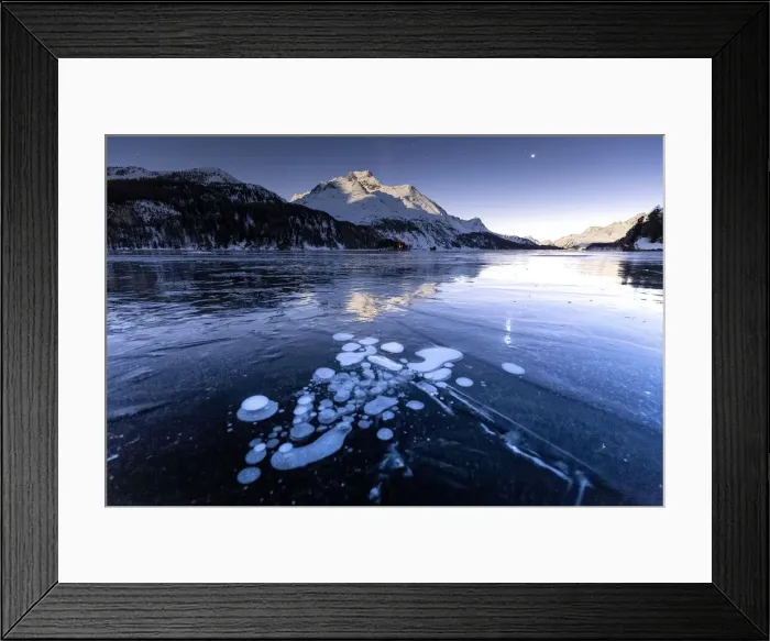 Framed Print : Methane bubbles in the icy surface of the lake with snowy peak illuminated by moonlight