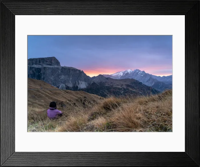 Framed Print : Rear view of woman sitting on grass admiring sunrise on Marmolada and Sass Pordoi Framed Print : Rear view of woman sitting on grass admiring sunrise on Marmolada and Sass Pordoi