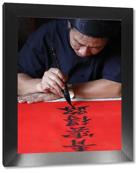 Man doing traditional Chinese writing (calligraphy) in ink using a brush