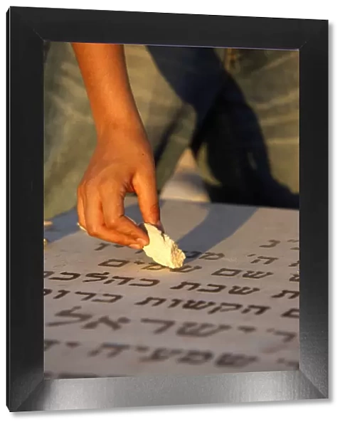 Boy placing stone on a grave in the Mount of Olives Jewish cemetery, Jerusalem, Israel