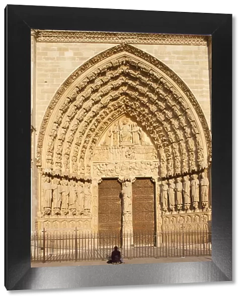 Woman praying in front of Last Judgment gate, west front, Notre Dame Cathedral