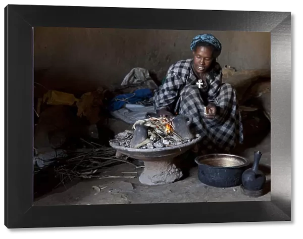 Ethiopian woman setting fire to boil the water for coffee for traditional ceremony