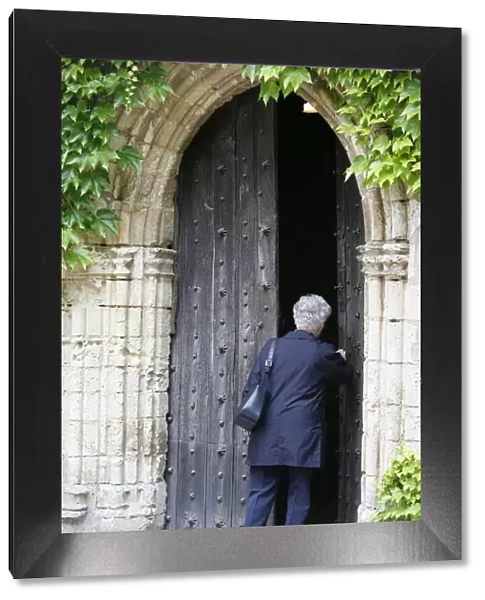 Woman walking into Saint-Pierre de Solesmes Abbey church, Solesmes, Sarthe