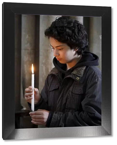 Teenager holding a candle in Notre Dame de Bayeux cathedral, Bayeux, Normandy, France