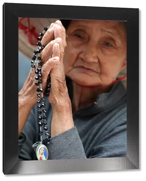 Old Vietnamese woman praying with prayer beads, St. Philip Church (Huyen Sy Church)