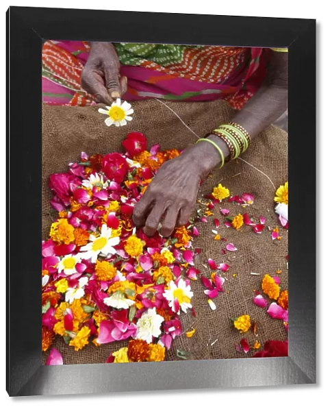 Woman making and selling garlands outside a Hindu temple, Goverdan, Uttar Pradesh, India