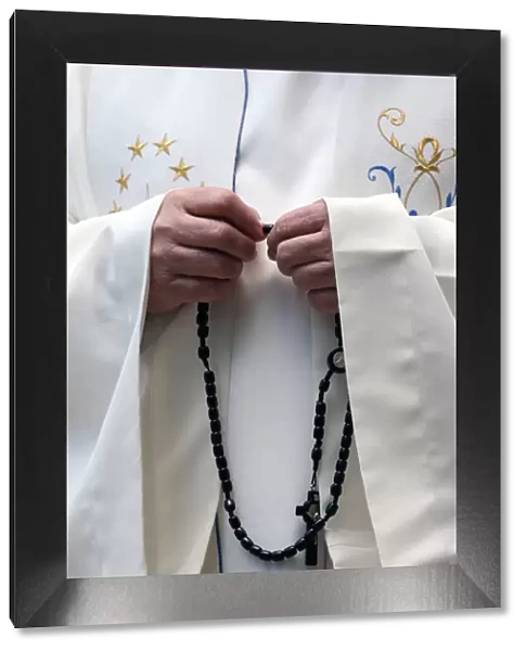 Hand-carved Roman Catholic rosary beads, priest praying The Mystery of the Holy Rosary