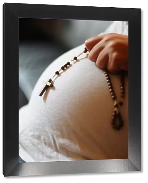 Pregnant woman with prayer beads, Paris, France, Europe