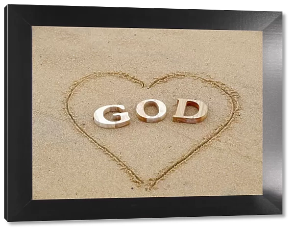 Wooden letters forming the word GOD with heart on a background of beach sand