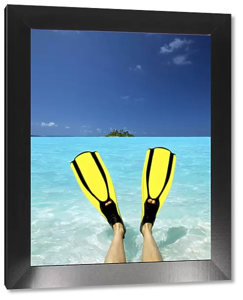 Tropical island and person wearing flippers sitting in sea, Maldives, Indian Ocean, Asia
