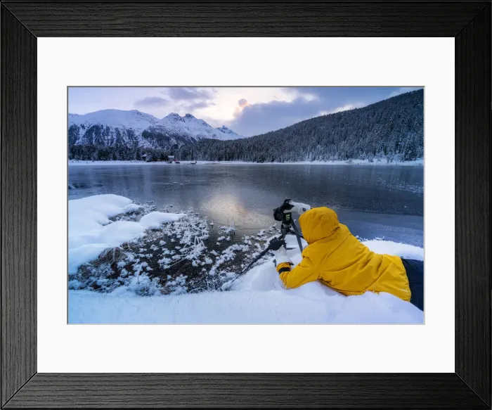 Framed Print : Photographer taking pictures of frozen Lej da Staz at dawn lying on the snow, Engadine