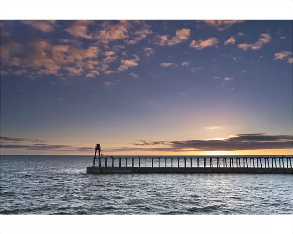 Sunrise over the North Sea and Whitby harbour and piers in late summer, Whitby