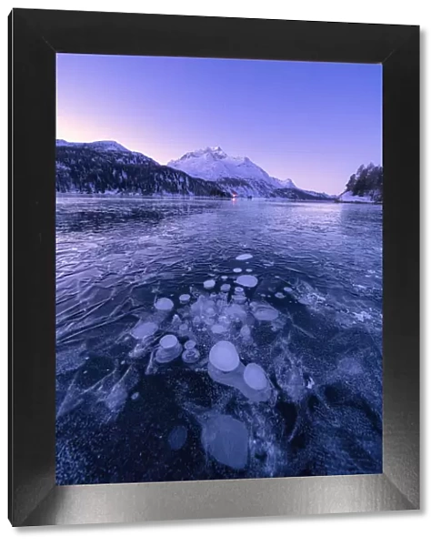 Ice bubbles trapped in Lake Sils with Piz Da La Margna in background at dawn, Engadine