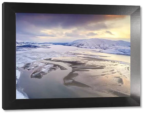 Aerial view of cold sea framed by snow capped mountains at sunset