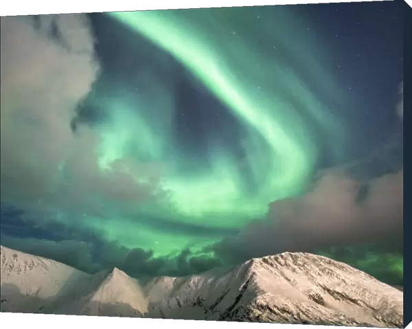 Northern Lights (Aurora Borealis) over mountain peaks covered with snow, Sorvaer