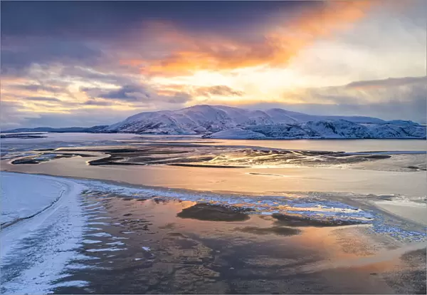 Sunset over the snow capped mountains and frozen sea in the pristine Tanamunningen Nature