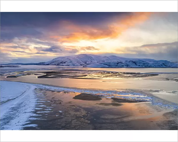 Sunset over the snow capped mountains and frozen sea in the pristine Tanamunningen Nature