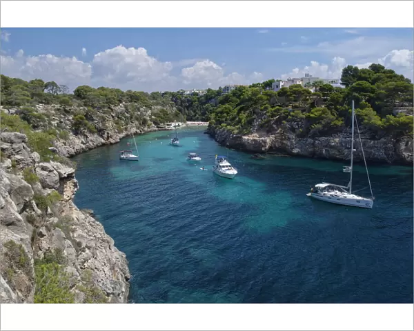 Yachts moored in the cove at Cala Pi, viewed from narrow cliff top coast path