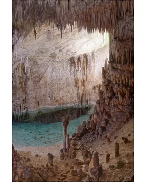 Flooded limestone cave interior with many stalactites and stalagmites and reflections