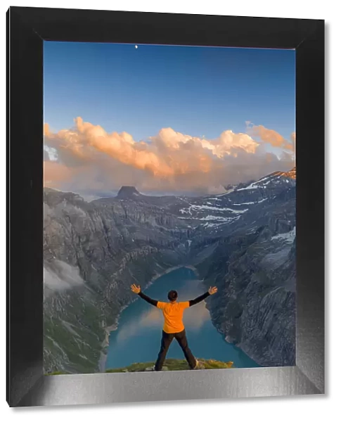 Man with outstretched arms enjoying sunset over lake Limmernsee standing on top of rocks