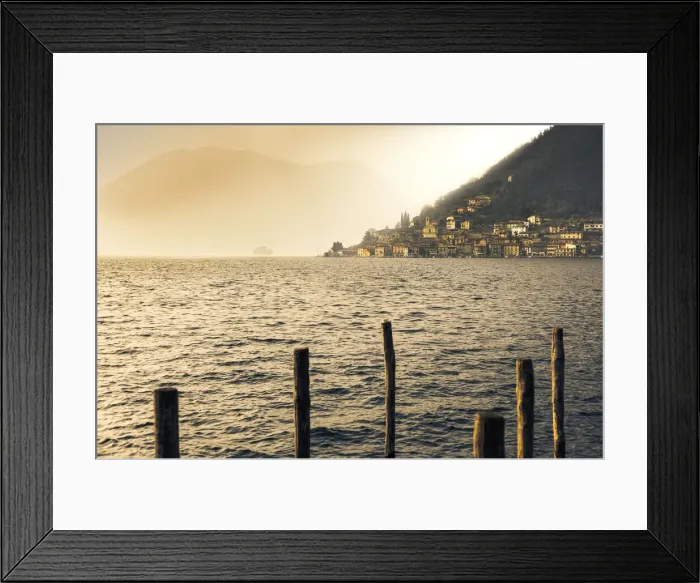 Framed Print : Light in the fog illuminates Peschiera Maraglio village, Monte Isola, Lake Iseo