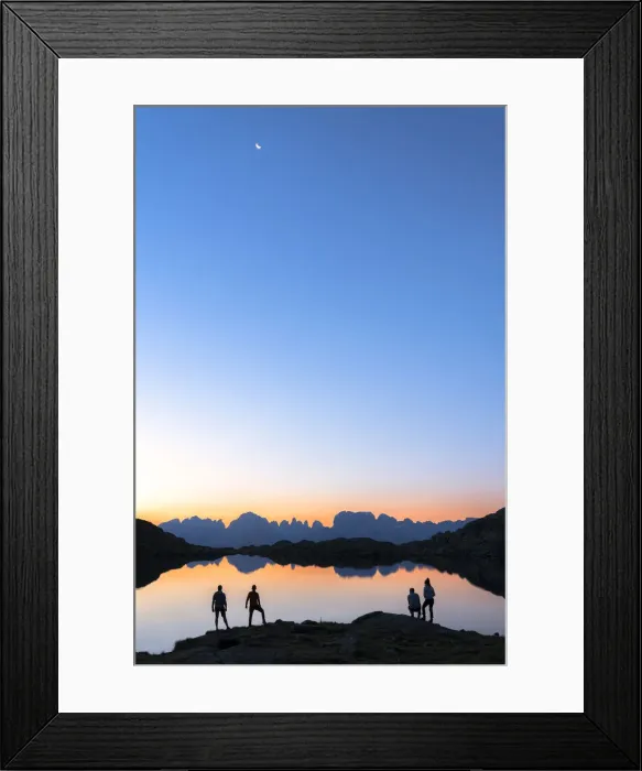 Framed Print : Hikers admiring Brenta Group Dolomites reflected in Lago Nero di Cornisello at dawn Framed Print : Hikers admiring Brenta Group Dolomites reflected in Lago Nero di Cornisello at dawn