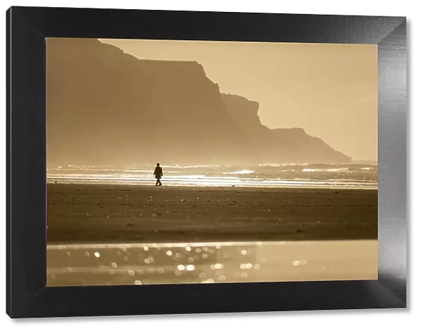 Person walking along beach in the evening sunlight, Rhossili, Gower Peninsula, Swansea