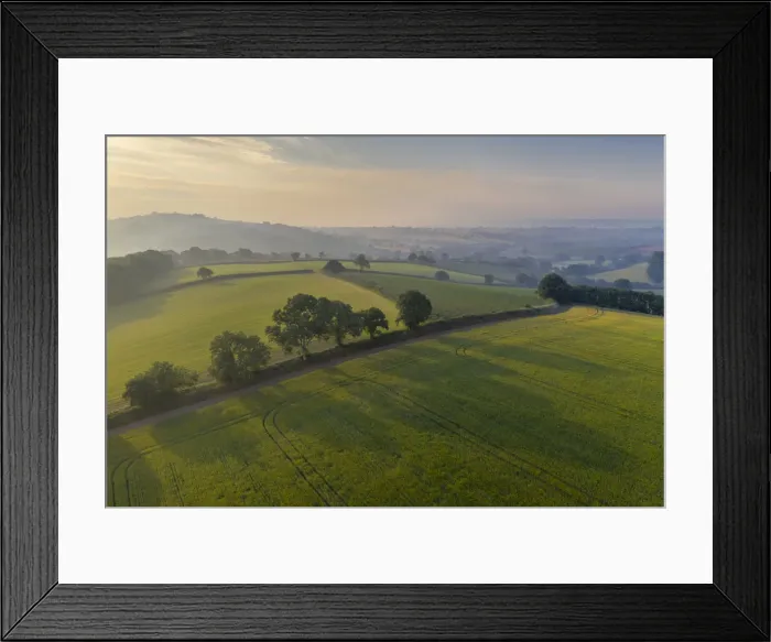 Framed Print : Aerial view of rolling countryside at dawn on a hazy summer day, Devon, England Framed Print : Aerial view of rolling countryside at dawn on a hazy summer day, Devon, England