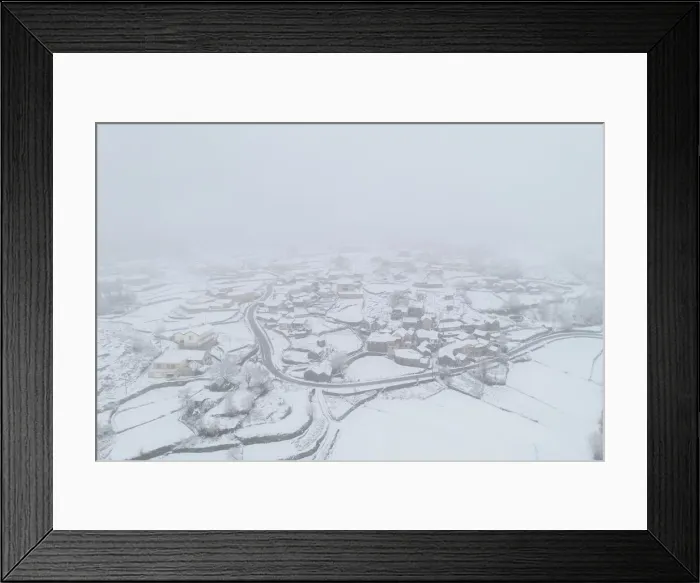 Framed Print : Drone aerial view of a road and remote village covered with snow in Vila Real, Norte Framed Print : Drone aerial view of a road and remote village covered with snow in Vila Real, Norte