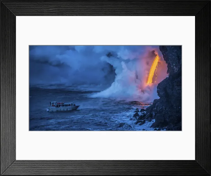 Framed Print : A tour boat observes lava pouring into the sea from 60 feet above as steam plumes billow Framed Print : A tour boat observes lava pouring into the sea from 60 feet above as steam plumes billow