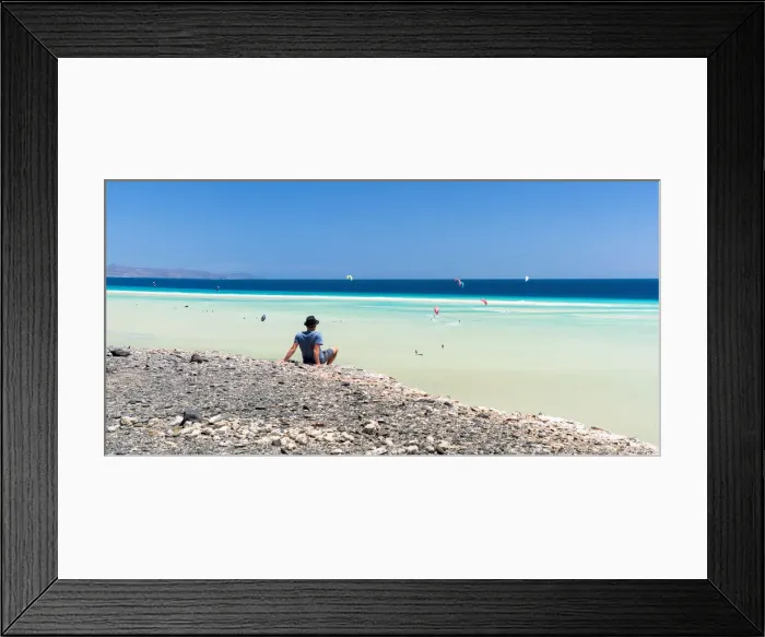 Framed Print : Man sitting on rocks looking at the kitesurfers in the clear sea, Sotavento beach, Jandia Framed Print : Man sitting on rocks looking at the kitesurfers in the clear sea, Sotavento beach, Jandia