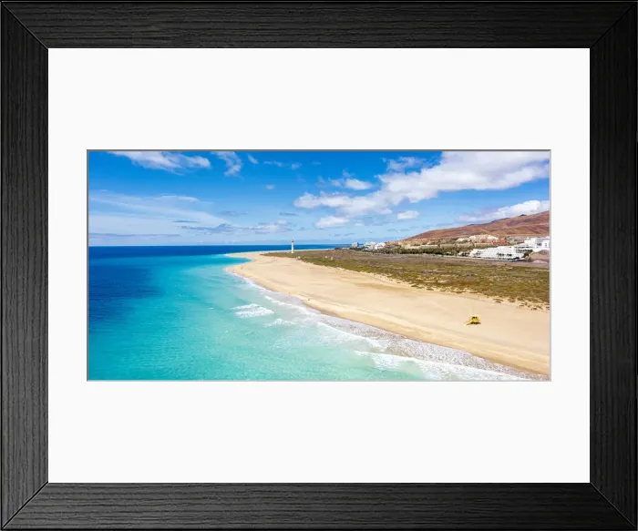 Framed Print : White sand beach washed by the turquoise sea with lighthouse in background, Morro Jable Framed Print : White sand beach washed by the turquoise sea with lighthouse in background, Morro Jable