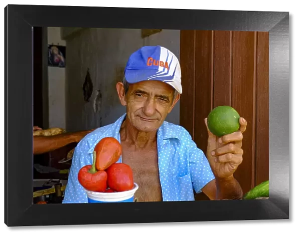 A man at a vegetable stand holds up a lime, Trinidad, Cuba, West Indies, Central America