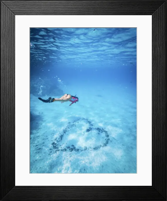 Framed Print : An athletic woman free-dives to inspect a heart arranged with rocks on the bottom of Framed Print : An athletic woman free-dives to inspect a heart arranged with rocks on the bottom of