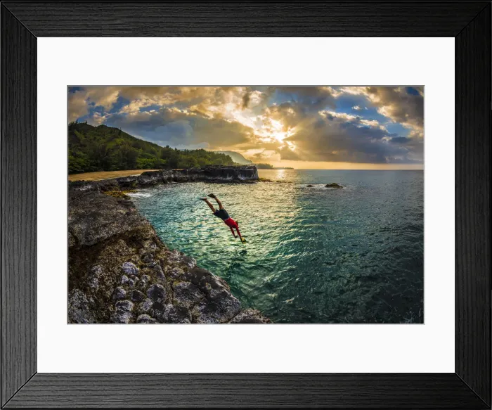 Framed Print : A young man dives into the calm sea on the northern rocky coastline of Kauai at sunset Framed Print : A young man dives into the calm sea on the northern rocky coastline of Kauai at sunset