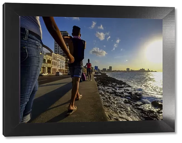 People walk along the Malecon as the sun sets, Havana, Cuba, West Indies, Central America