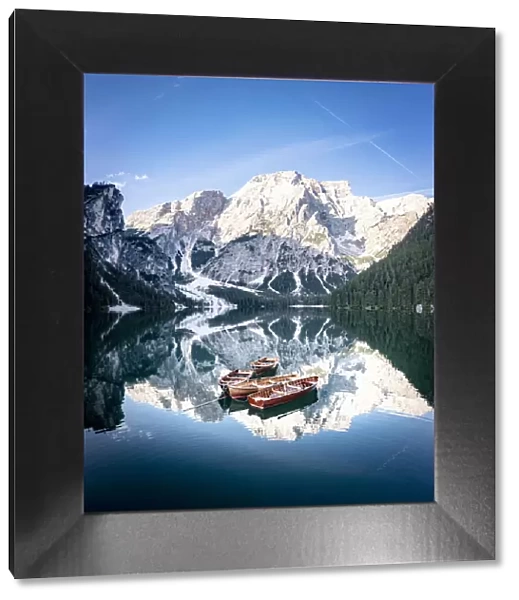 Boats moored in Lake Braies (Pragser Wildsee) with mountains reflected in water at