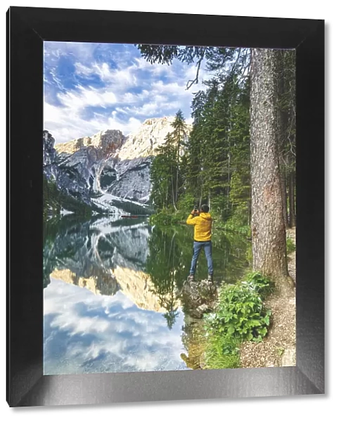 Hiker man photographing Lake Braies (Pragser Wildsee) with smartphone at sunrise