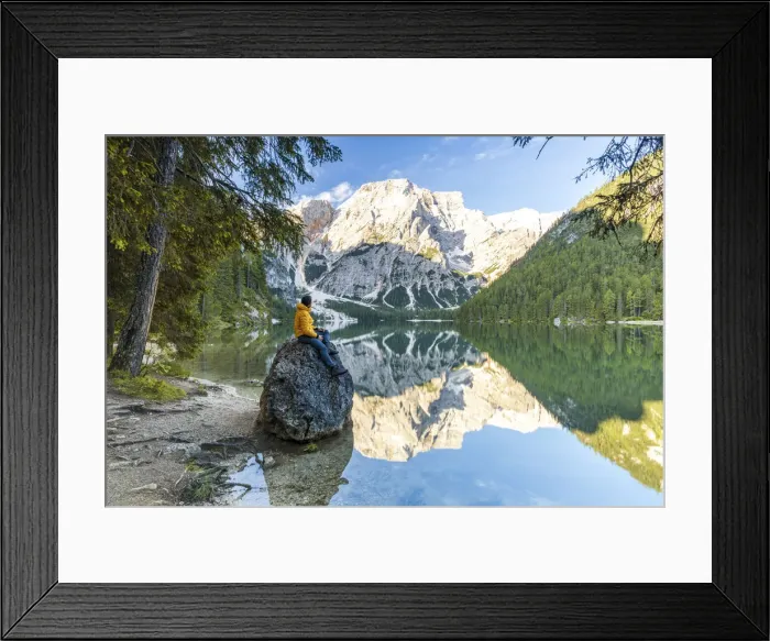 Framed Print : Hiker man enjoying sunrise sitting on rocks on shore of Lake Braies (Pragser Wildsee Framed Print : Hiker man enjoying sunrise sitting on rocks on shore of Lake Braies (Pragser Wildsee