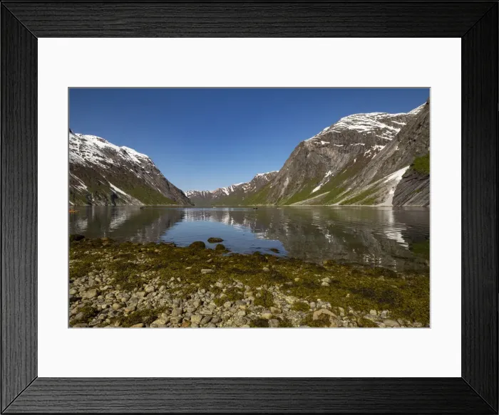 Framed Print : Snow capped mountains reflected in the still waters of the fjord where kayakers are Framed Print : Snow capped mountains reflected in the still waters of the fjord where kayakers are