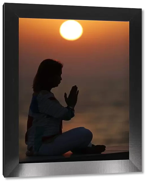 Woman practising yoga pose and meditation at sunset as concept for silence and relaxation