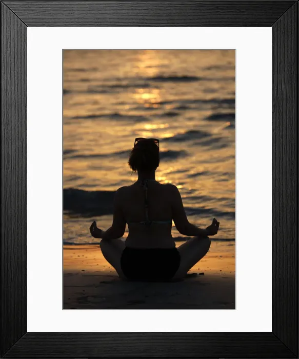 Framed Print : Woman practising yoga meditation on beach at sunset as concept for silence and relaxation