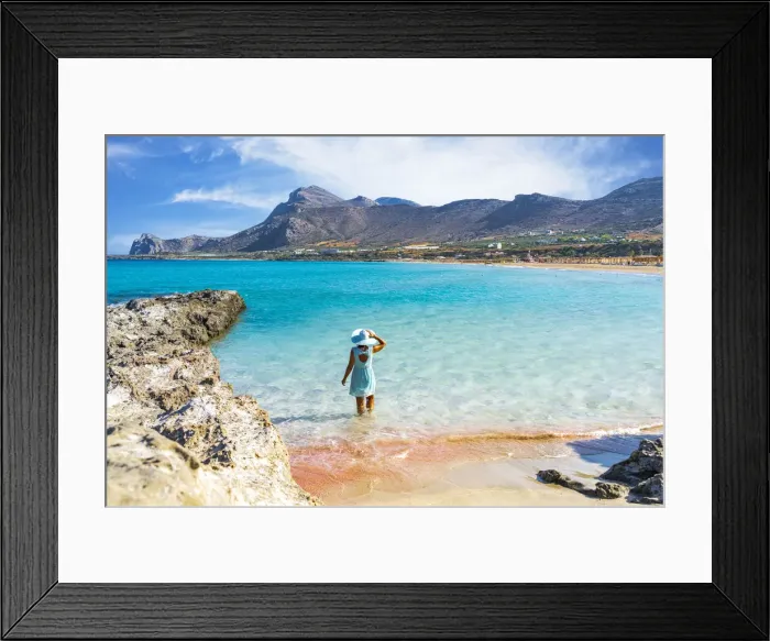 Framed Print : Woman in dress standing in the turquoise clear sea facing the pink sand beach of Framed Print : Woman in dress standing in the turquoise clear sea facing the pink sand beach of