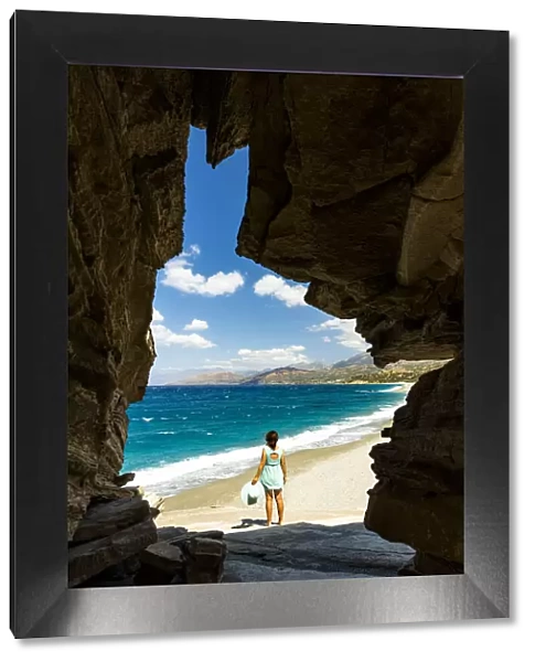Rear view of young woman admiring the crystal sea from natural cave on Triopetra beach