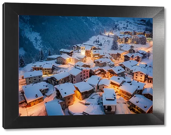 Christmas lights on mountain houses and chalets covered with snow at dusk, Pianazzo