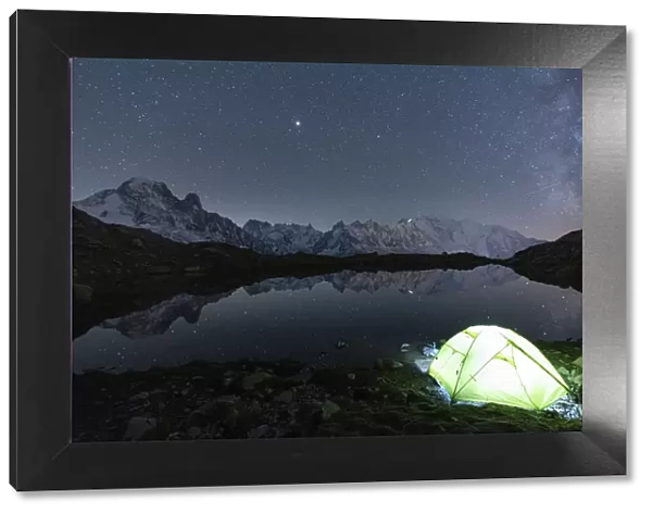 Illuminated tent under the stars at Lacs des Cheserys with Mont Blanc massif reflected in