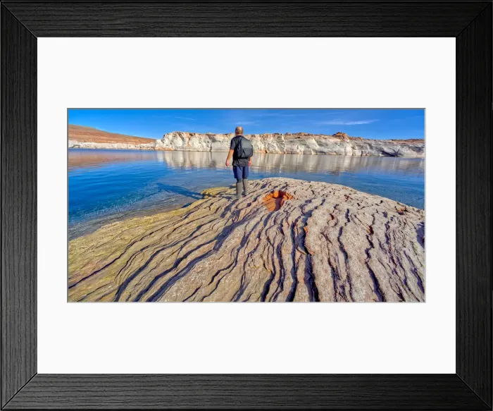 Framed Print : Man hiking along rocky shoreline of Lake Powell in an area called the Chains in the Glen