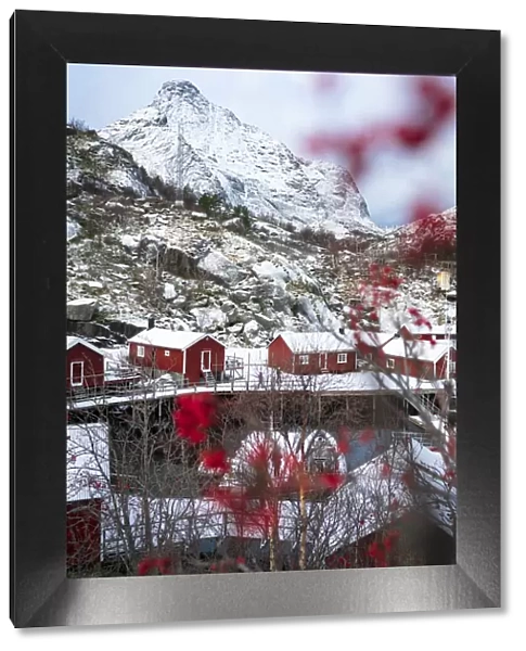 Red Rorbu cabins framed by snowcapped mountains in winter, Nusfjord, Nordland county, Lofoten Islands, Norway, Scandinavia, Europe